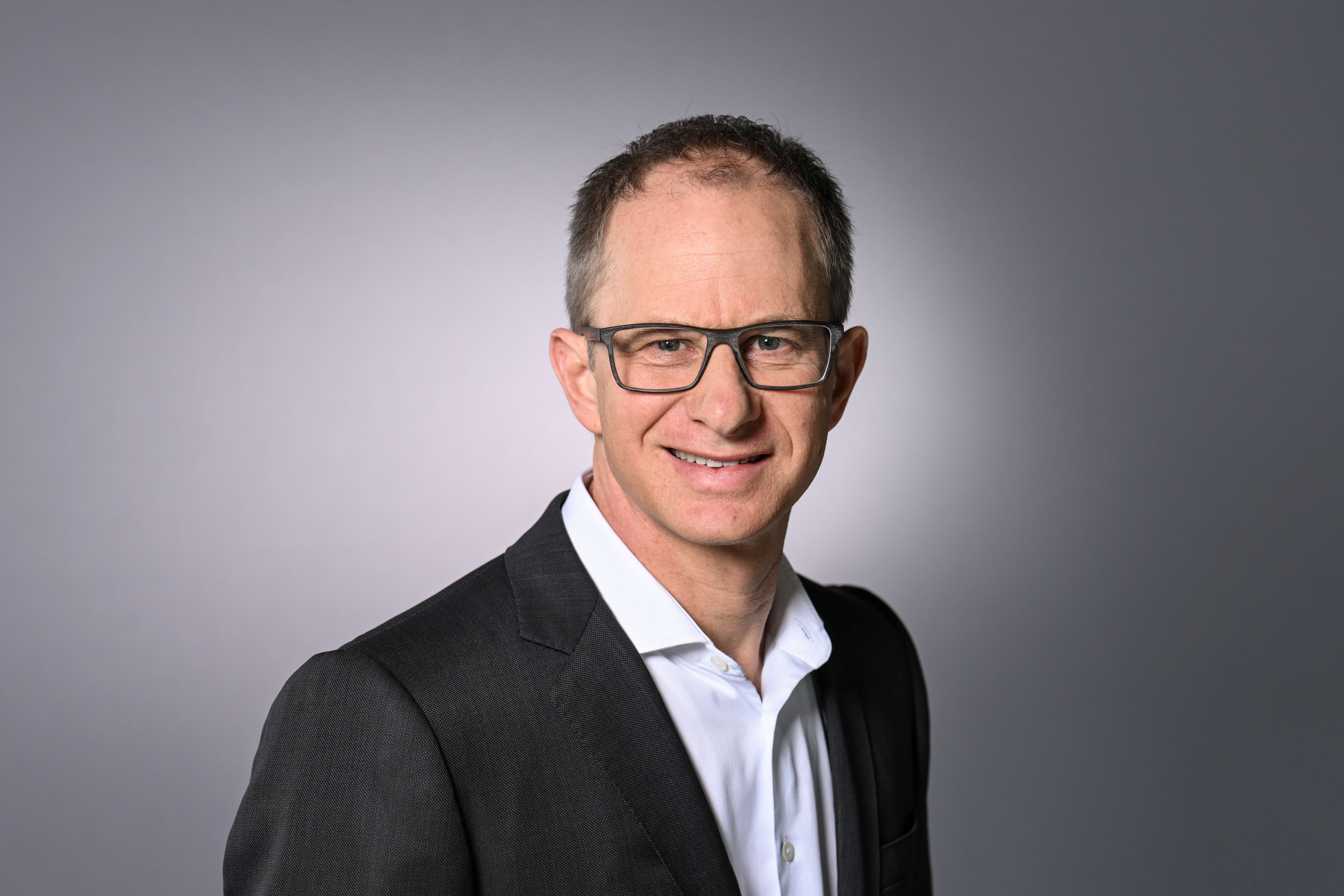 Man wearing glasses and a suit smiling