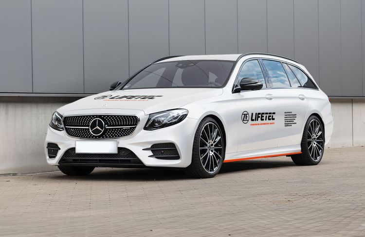 Weißer Mercedes-Benz Kombi mit ZF Lifetec-Branding, der automobile Sicherheitstechnologie präsentiert.