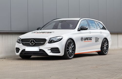 Weißer Mercedes-Benz Kombi mit ZF Lifetec-Branding, der automobile Sicherheitstechnologie präsentiert.